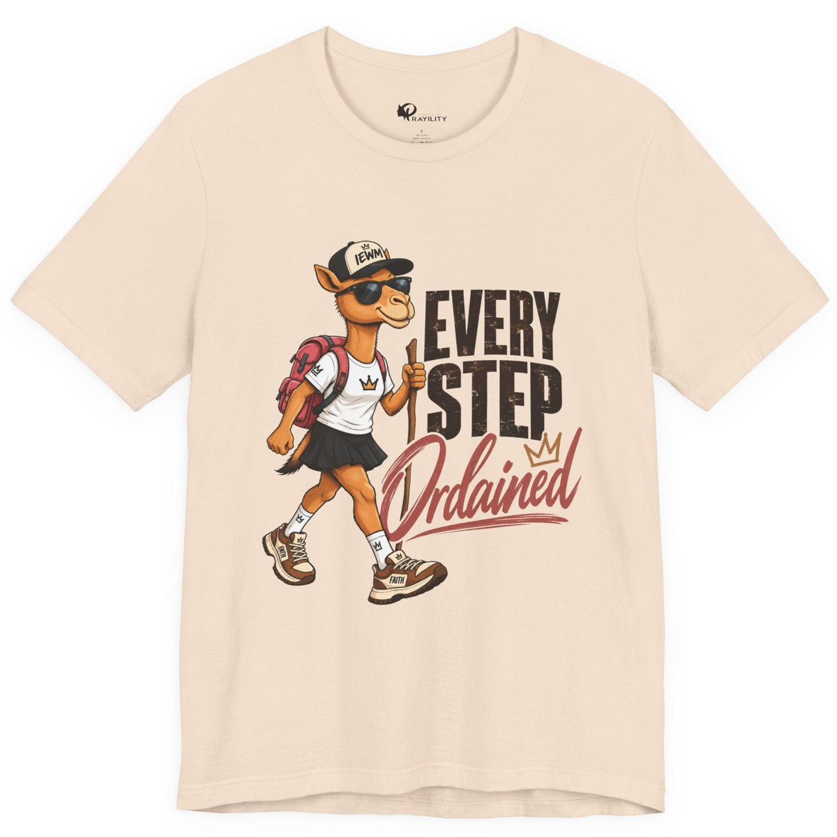 A light beige crewneck t-shirt featuring a graphic print of a walking camel mascot wearing sunglasses and a cap next to the text 'EVERY STEP Ordained'.