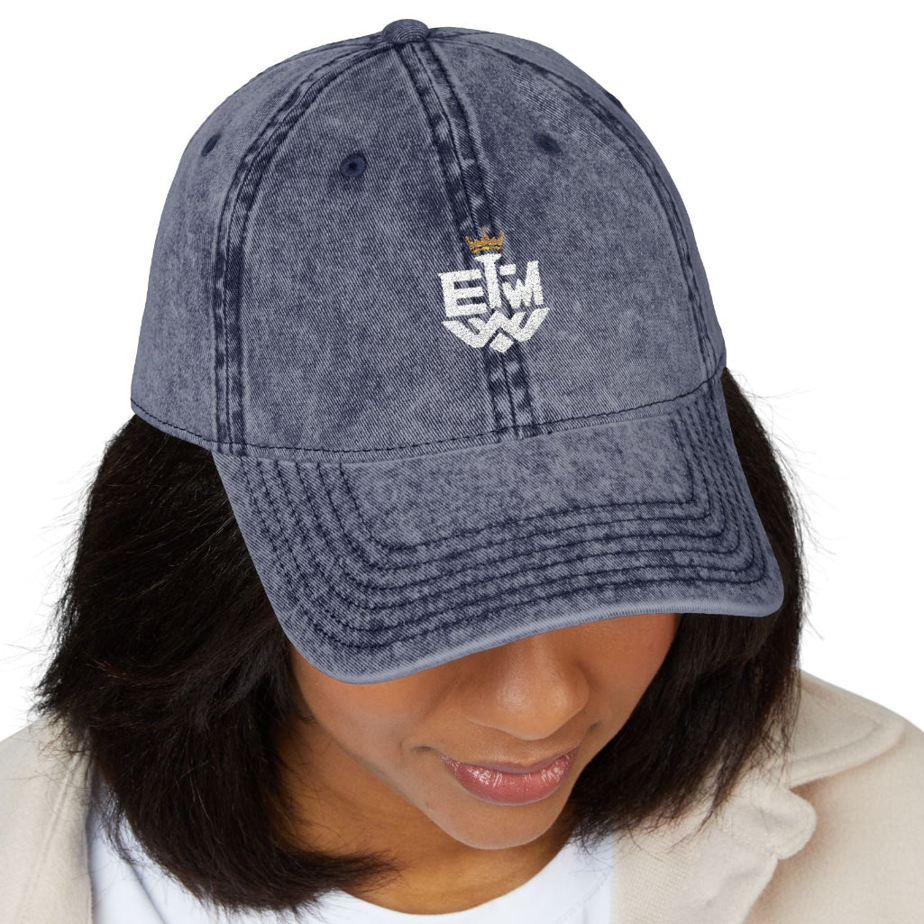 Person wearing a blue denim cap with a white graphic and text on a white background