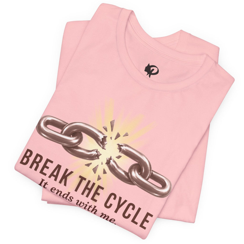 A folded light pink t-shirt with a graphic of a broken metal chain and the text 'BREAK THE CYCLE It ends with me' printed on the front, set against a plain white background.