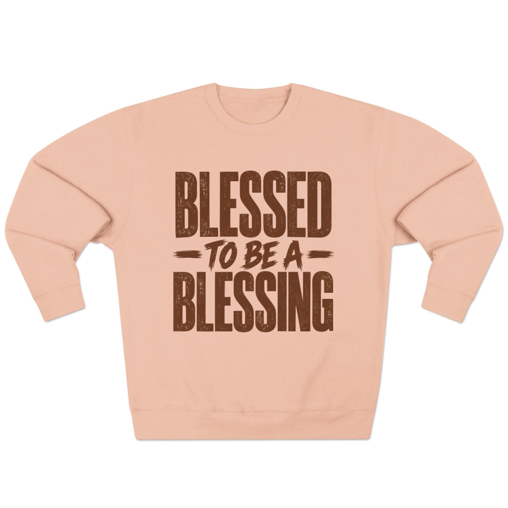 A pale pink crewneck sweatshirt with the phrase 'BLESSED TO BE A BLESSING' printed in a distressed brown font on the front, displayed against a solid white background.